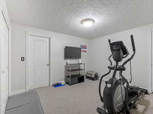 Exercise room with a textured ceiling and light colored carpet