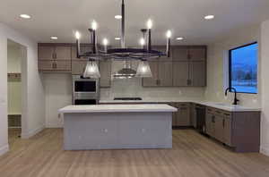 Kitchen featuring a center island, backsplash, stainless steel appliances, light wood-type flooring, and recessed lighting