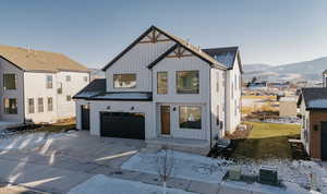 Modern farmhouse featuring a mountain view, board and batten siding, a garage, driveway, and roof with shingles