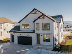 Modern farmhouse featuring a mountain view, board and batten siding, a garage, driveway, and roof with shingles