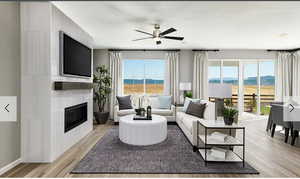 Living area with light wood-type flooring, a glass covered fireplace, and a ceiling fan