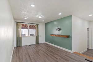 Empty room featuring wood finished floors, recessed lighting, and a textured ceiling