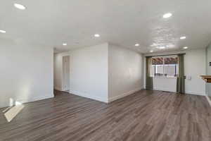 Unfurnished living room featuring recessed lighting, dark wood finished floors, and a textured ceiling