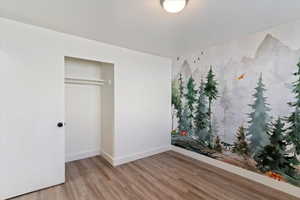 Unfurnished bedroom with wood finished floors and a closet