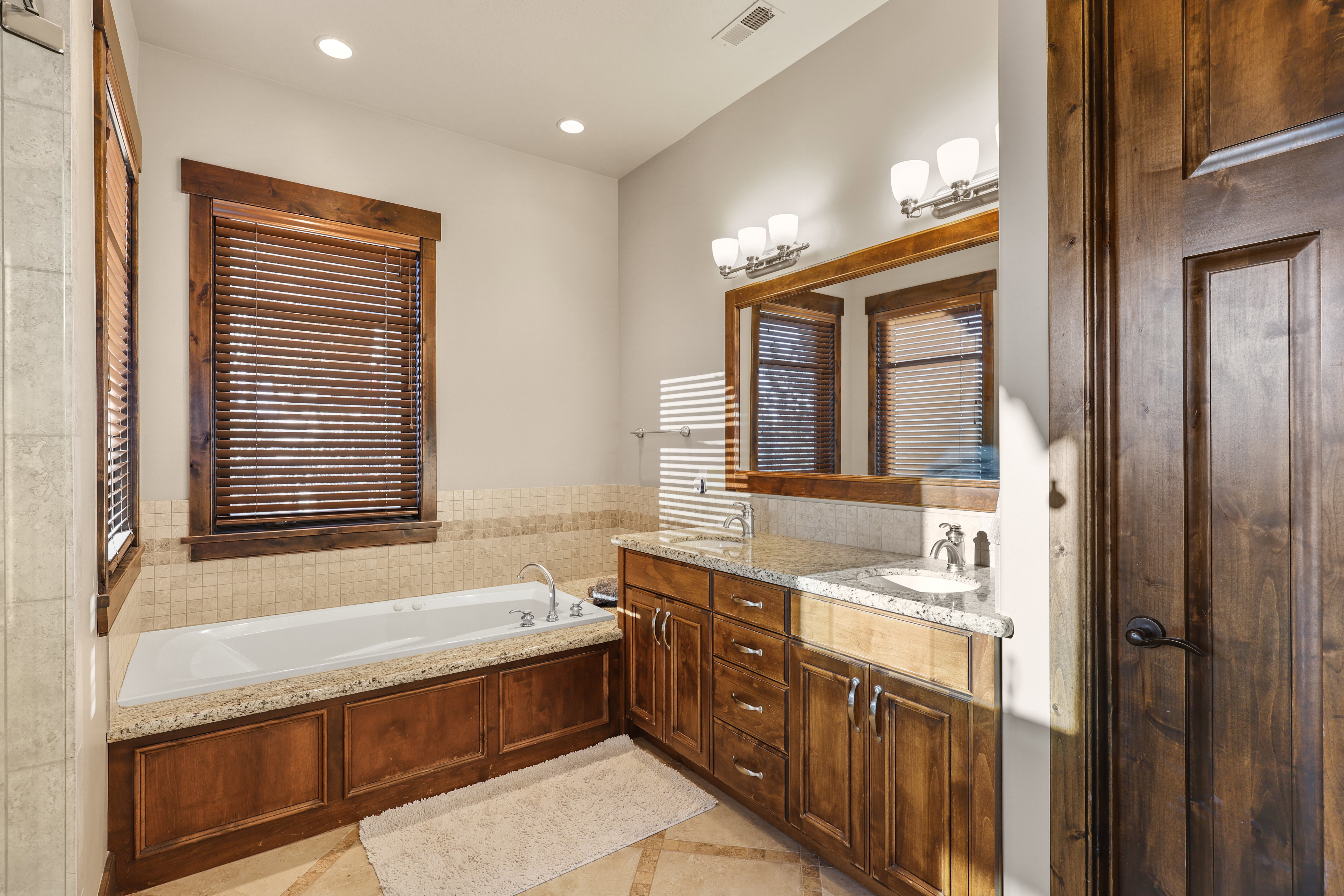 Bathroom with double vanity, a bath, recessed lighting, and inlaid floor details