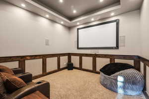 Carpeted home theater featuring a wainscoted wall, recessed lighting, and a raised ceiling