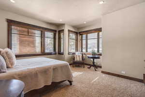 Carpeted bedroom featuring multiple windows and recessed lighting