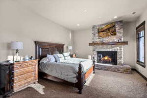 Bedroom with carpet floors, a stone fireplace, and recessed lighting