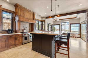 Kitchen featuring a kitchen bar, double oven range, pendant lighting, recessed lighting, and brown cabinetry