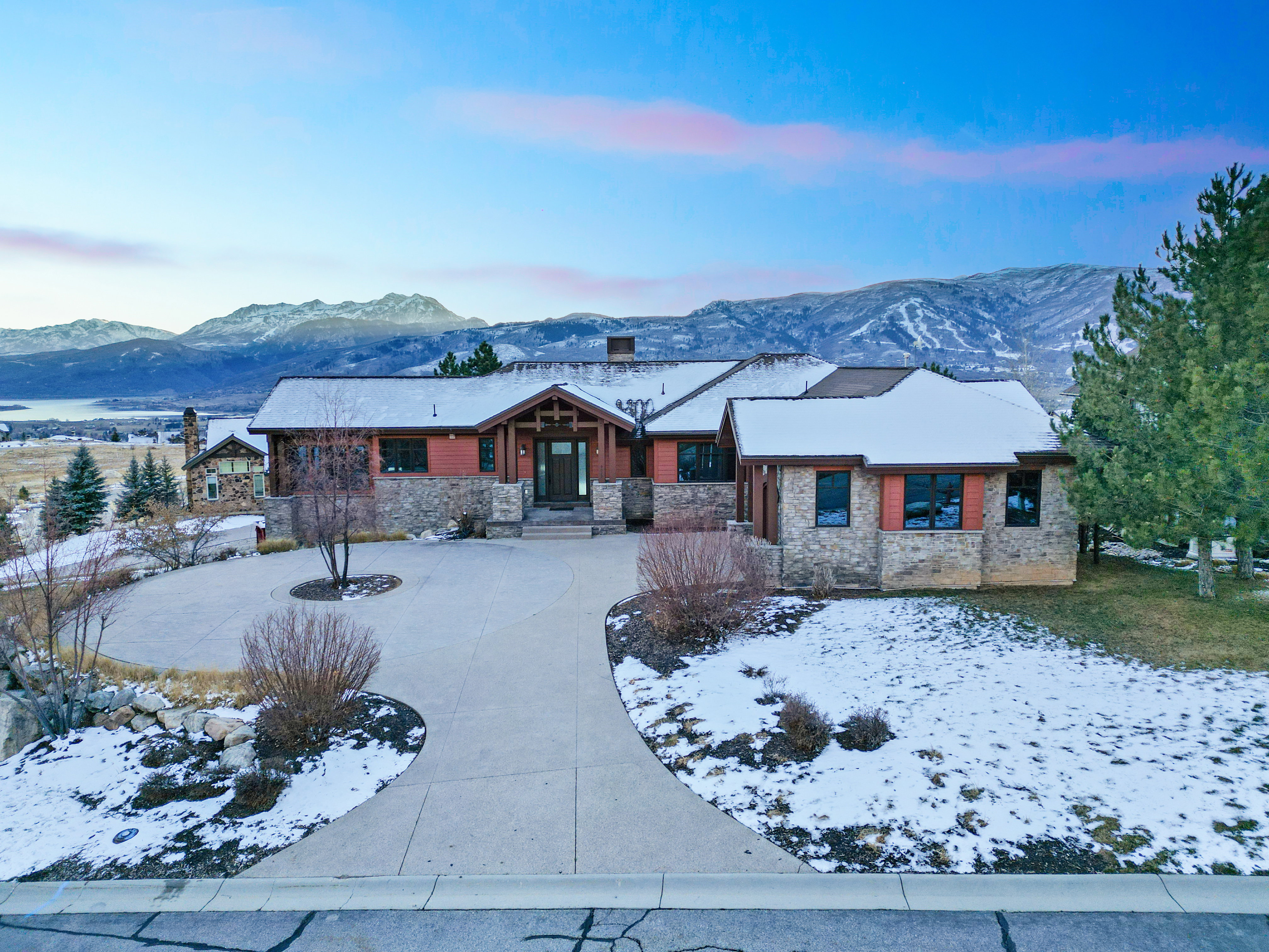 View of front of home featuring a mountain view, a chimney, curved driveway, and stone siding