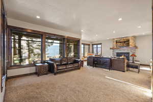 Living room with light colored carpet, a stone fireplace, and recessed lighting