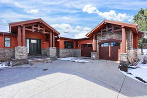 View of front of property with stone siding, driveway, and a garage