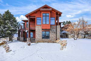 View of front of house with stone siding and a balcony
