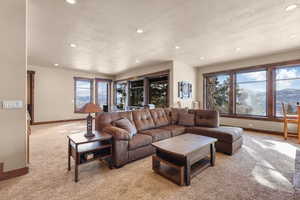 Living area featuring carpet flooring, recessed lighting, and a textured ceiling