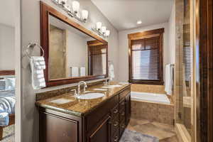 Full bath featuring double vanity, a shower stall, tiled bath, and light tile patterned floors