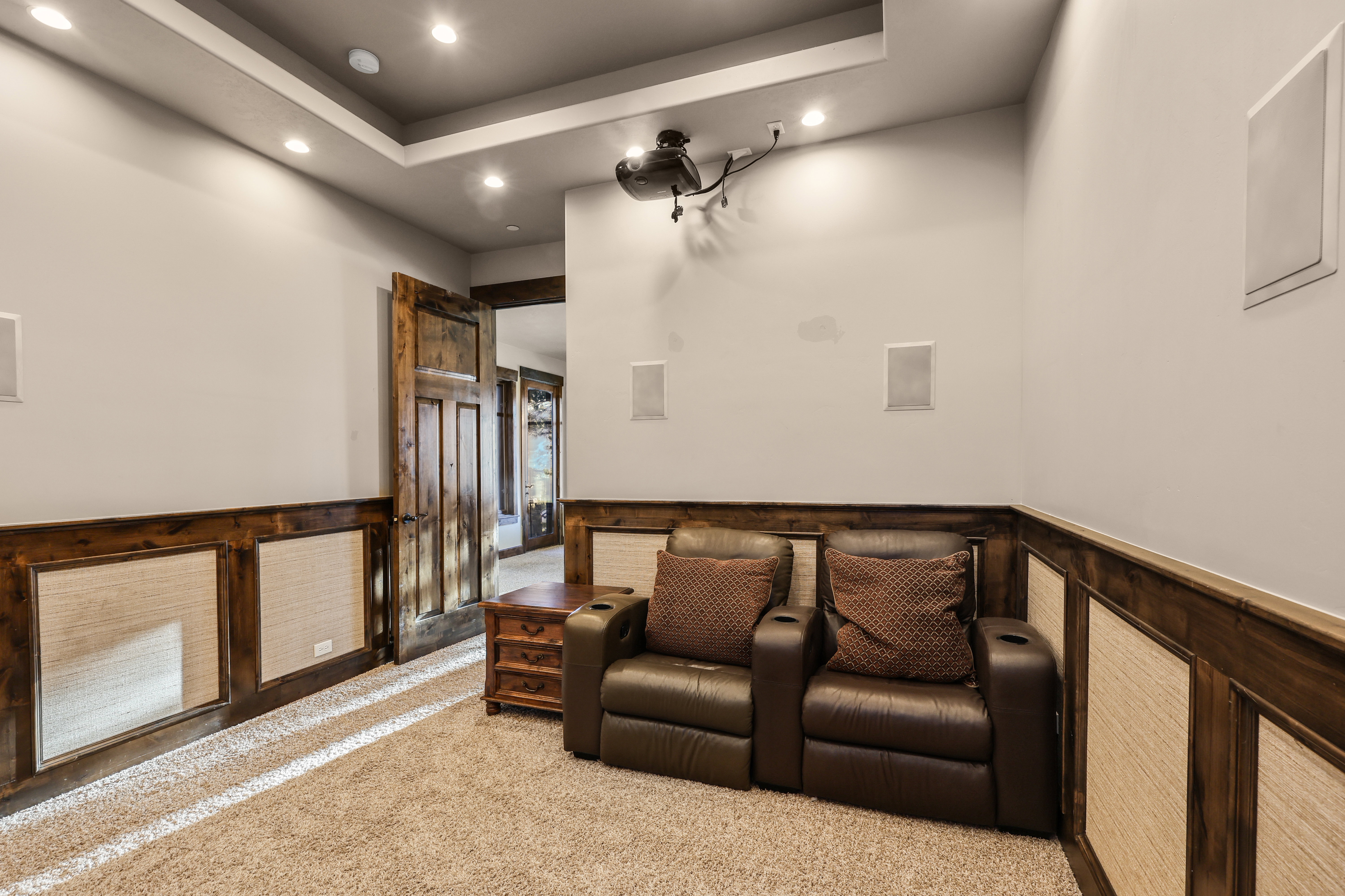 Cinema featuring a wainscoted wall, recessed lighting, a tray ceiling, carpet, and a decorative wall