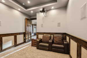 Cinema featuring a wainscoted wall, recessed lighting, a tray ceiling, carpet, and a decorative wall