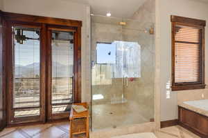 Bathroom with inlaid floor details, a shower stall, plenty of natural light, and light tile patterned flooring