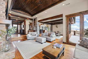 Living area featuring wood-type flooring, wooden ceiling, healthy amount of natural light, ornate columns, and recessed lighting