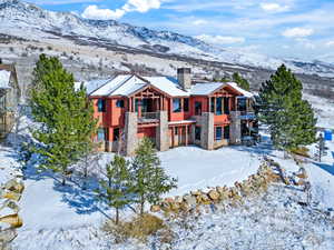 View of front facade featuring a balcony, a chimney, stone siding, and a mountain view