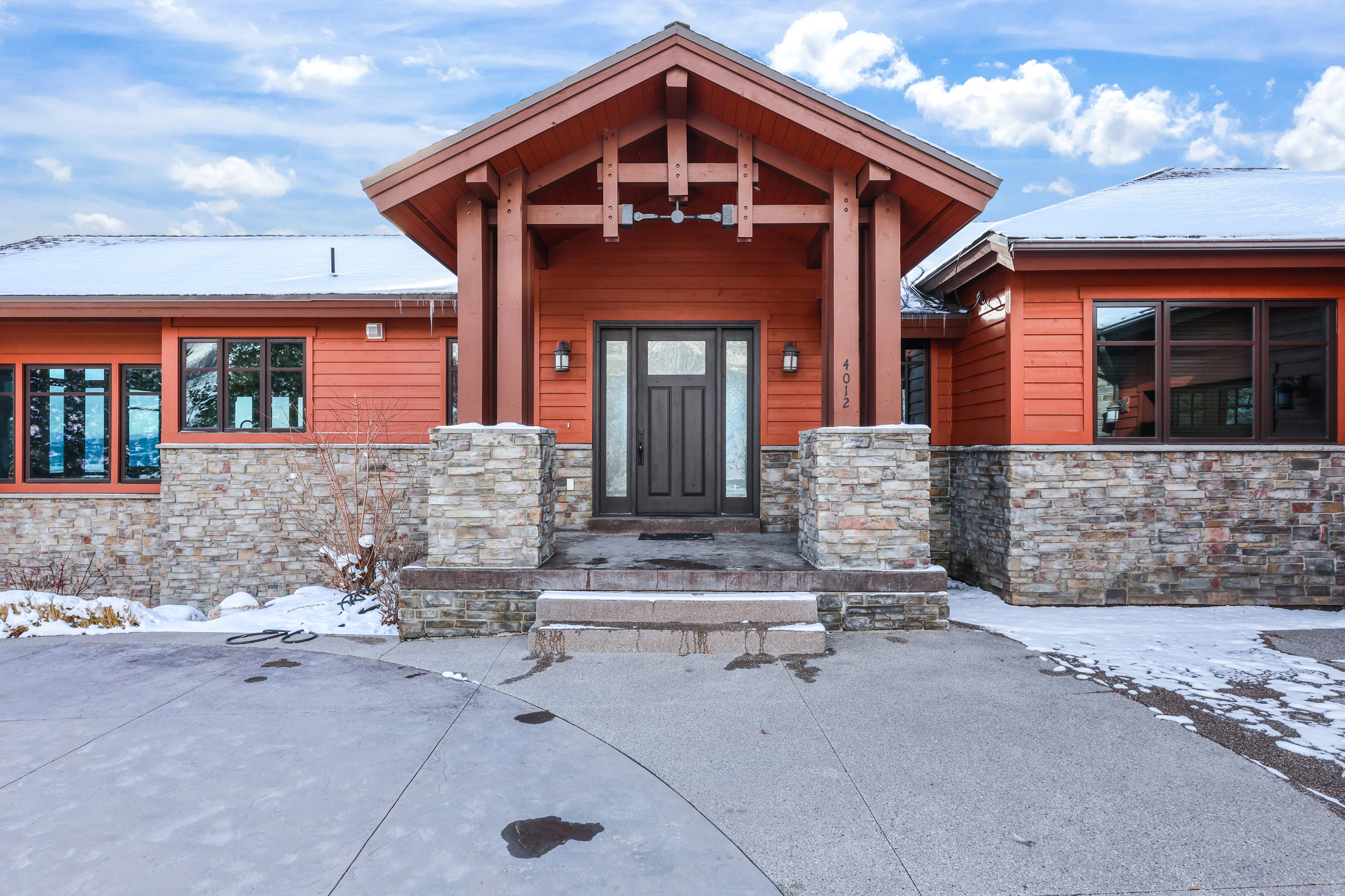 Snow covered property entrance featuring stone siding