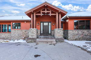 Snow covered property entrance featuring stone siding