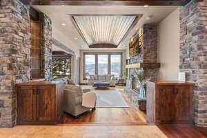 Living room featuring hardwood / wood-style floors, a tray ceiling, a stone fireplace, recessed lighting, and wooden ceiling