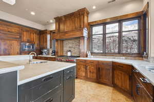 Kitchen with backsplash, stainless steel microwave, recessed lighting, and light stone countertops
