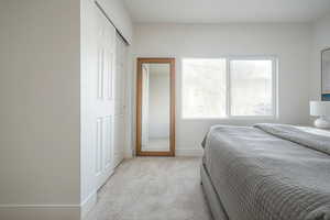 Bedroom featuring light colored carpet and a closet