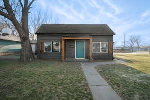 Bungalow-style home with a shingled roof and a front lawn