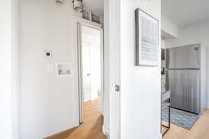 Hallway with crown molding and light wood-type flooring