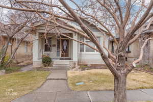 Bungalow featuring brick siding, a front lawn, and covered porch