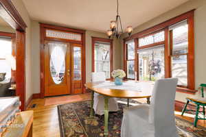 Dining space with healthy amount of natural light, light wood finished floors, and a chandelier