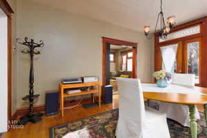 Dining area with wood finished floors, a chandelier, french doors, and a textured ceiling