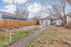 Rear view of house with entry steps, a shed, stucco siding, and roof with shingles
