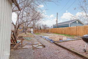 Fenced backyard with a patio and a vegetable garden