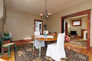 Dining room with hardwood / wood-style flooring, a chandelier, a fireplace, and a textured ceiling
