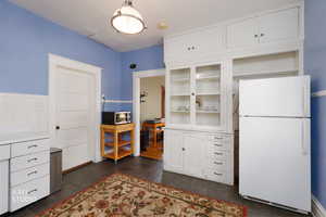 Kitchen with white cabinets, freestanding refrigerator, light countertops, and stainless steel microwave