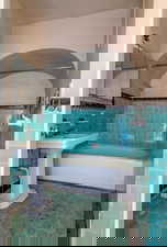 Full bathroom featuring tile walls, shower / washtub combination, a wainscoted wall, and dark tile patterned floors