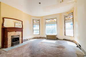 Unfurnished living room with radiator and a tiled fireplace