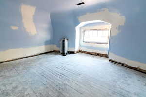 Bonus room with wood-type flooring and radiator