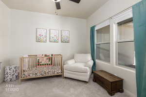 Bedroom featuring carpet floors, a ceiling fan, and a crib