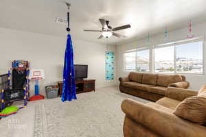 Living area featuring carpet, a ceiling fan, and a textured ceiling