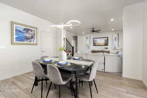 Dining area featuring stairway, light wood-type flooring, ceiling fan, recessed lighting, and a chandelier
