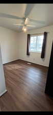 Empty room featuring dark wood-style flooring and ceiling fan