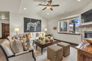 Living room with vaulted ceiling, a fireplace, a ceiling fan, and recessed lighting