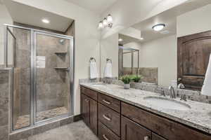Full bath with double vanity, a shower stall, and light tile patterned floors