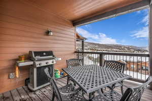 Snow covered deck featuring grilling area, outdoor dining space, and a mountain view