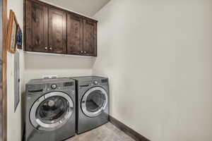Laundry room with cabinet space, washer and dryer, and light tile patterned flooring