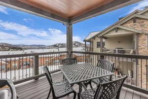 Snow covered deck featuring a mountain view and outdoor dining space